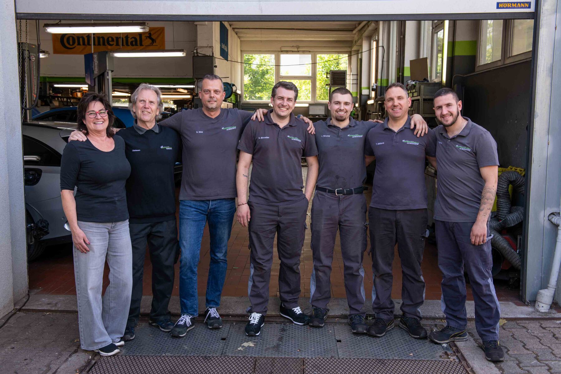 Teamfoto in der geöffneten Werkstatthalle